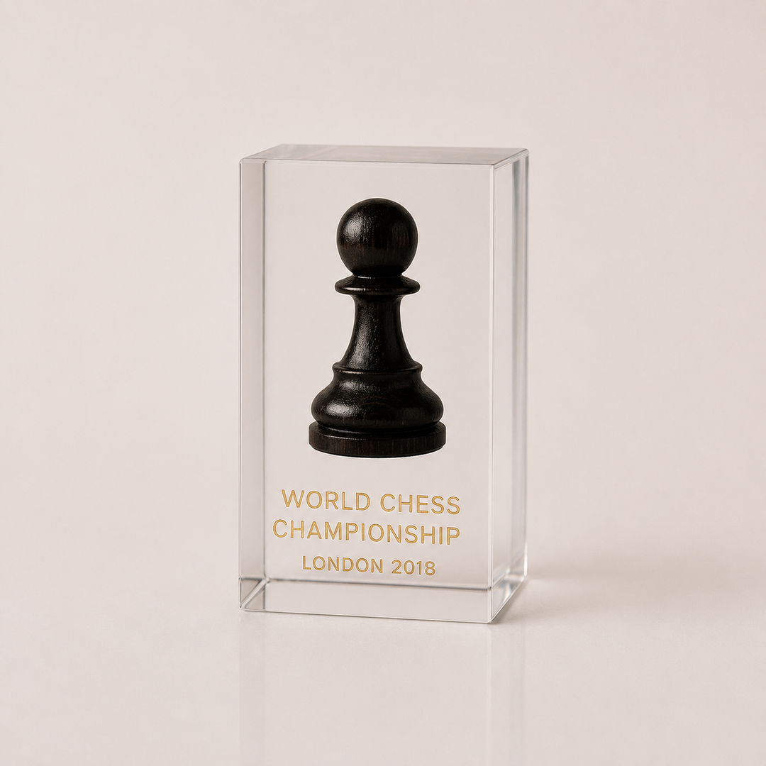 Black chess pawn in a clear glass case with 'World Chess Championship London 2018' text on a beige background